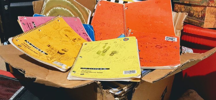 old notebooks with scribbled covers in a broken-down box